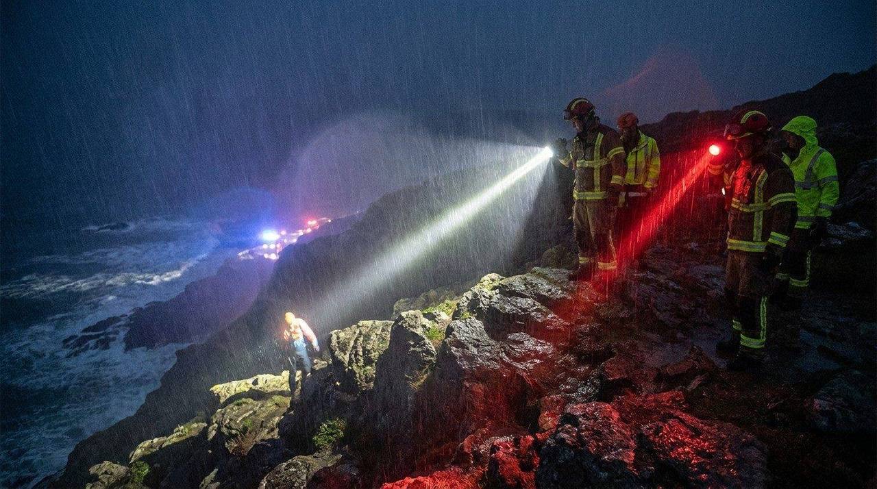 Mountain rescue team at night using powerful headlamps on a rocky ridge